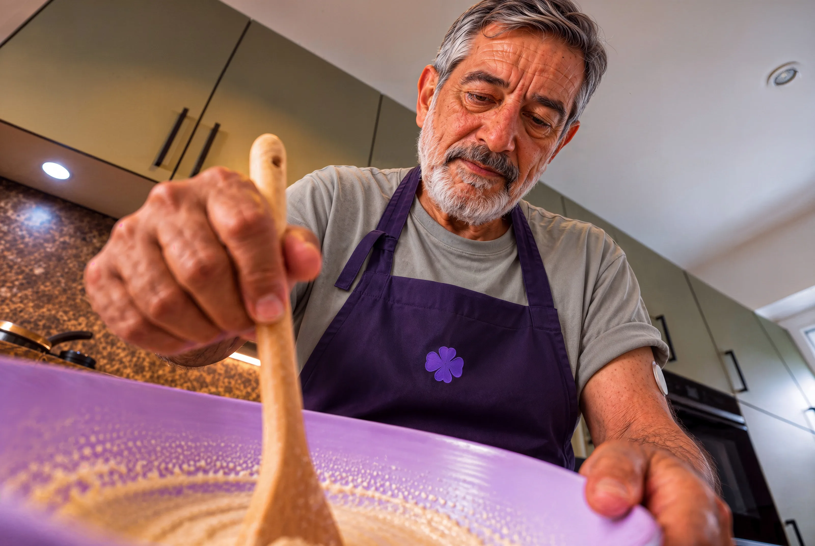 Ein Mann mit Schürze rührt mit einem Holzlöffel in einer Schüssel.