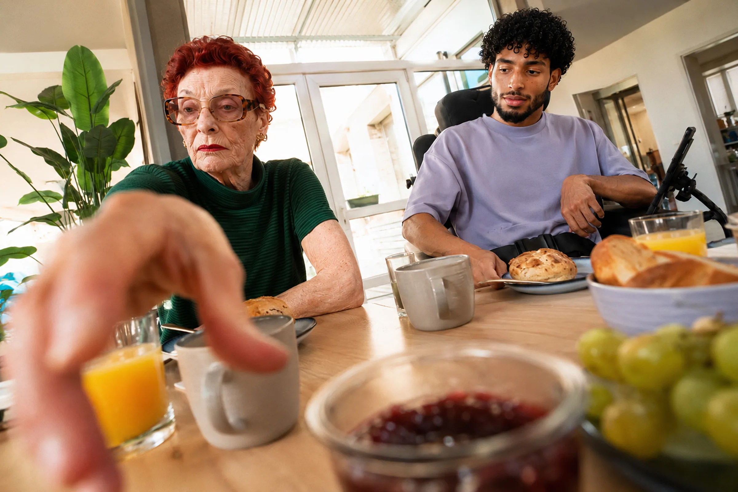 Frühstückstisch mit zwei Personen, Saft, Marmelade und Trauben.